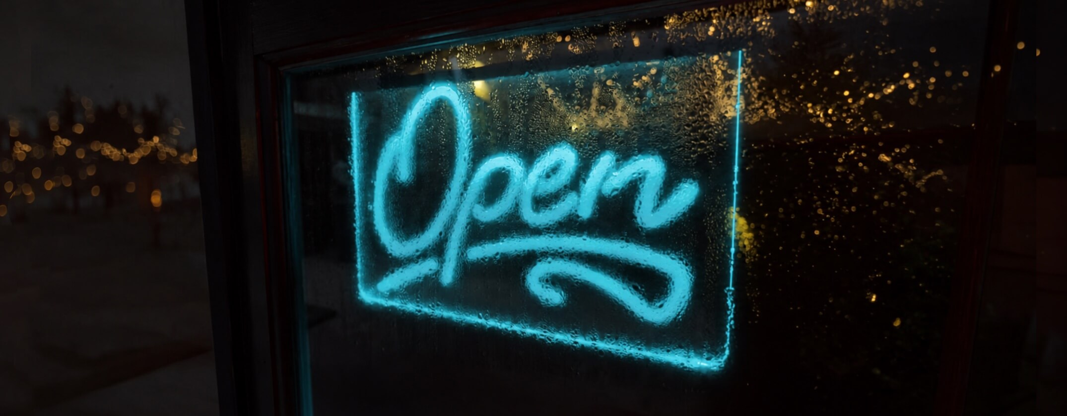 Ein blau leuchtendes „Open“-Neonschild bei Nacht.